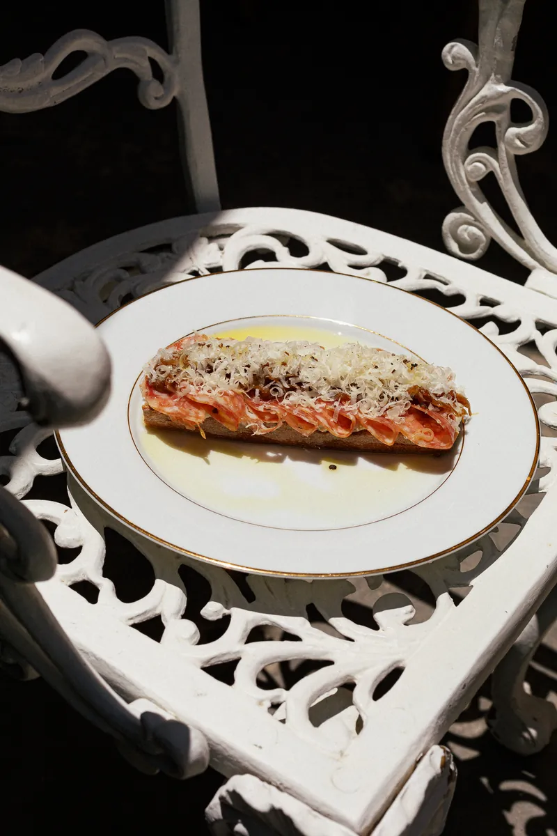 Bruschetta de salame con crema de alcachofa, pecorino y cebolla caramelizada